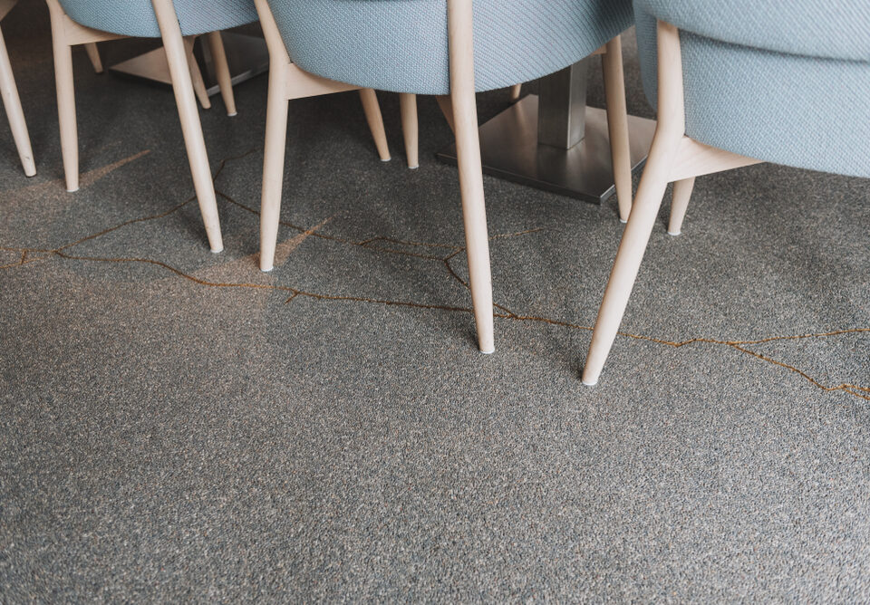 Row of modern chairs with wooden legs on a cracked concrete floor in a cafe or restaurant